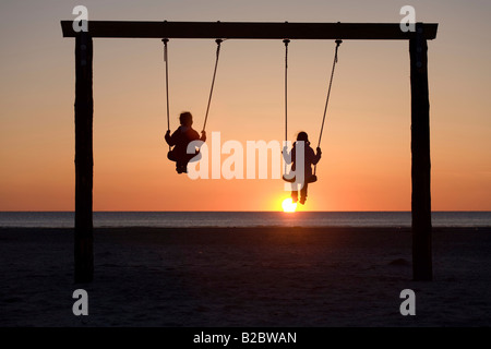 Due ragazze, 8- e 12-anno-vecchio, guardando un tramonto sul Mare del Nord, San Peter-Ording, Frisia settentrionale, Schleswig-Holstein, Germania settentrionale Foto Stock