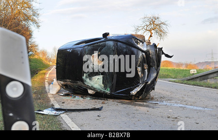 Auto giacente sul suo lato dopo un incidente, in primo piano una strada post riflettente, Ohmden, Esslingen county Foto Stock