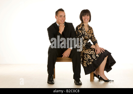 Uomo e donna nei primi anni venti seduta su una panchina Foto Stock