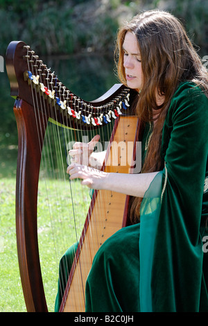 Musicista femmina in costume medievale riproduzione di un arpa celtica durante il Renaissancefest o Renaissance festival a moated il cast Foto Stock