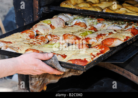 La mano tirando un vassoio da forno riempita con pane pizza al di fuori di un forno rustico, Renania settentrionale-Vestfalia, Germania, Europa Foto Stock