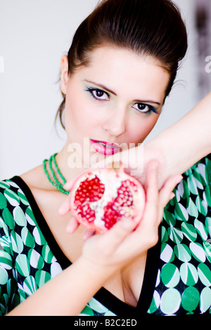 Donna attraente tenendo metà del melograno Foto Stock