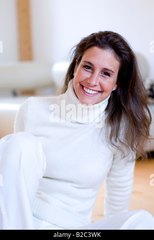 Giovane donna seduta sul pavimento e ridere Foto Stock
