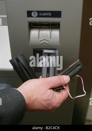 Dipendente della Banca dimostrando dispositivi tecnici utilizzati dai criminali per spiare i numeri e codici pin di carte bancarie in una macchina ATM Foto Stock