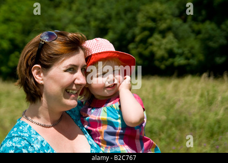 Ritratto orizzontale di diciotto mesi di età bambina e la sua giovane madre in campagna su una luminosa giornata di sole. Foto Stock
