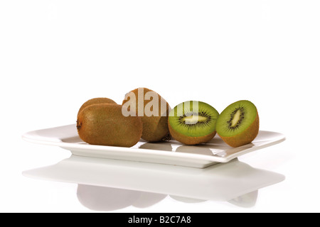 Kiwi (Actinidia deliciosa) tagliate a metà, su di una piastra Foto Stock