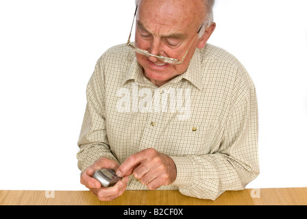 Ritratto orizzontale di un anziano gentiluomo ottenere frustrati utilizzando i pulsanti piccoli su un telefono cellulare Foto Stock