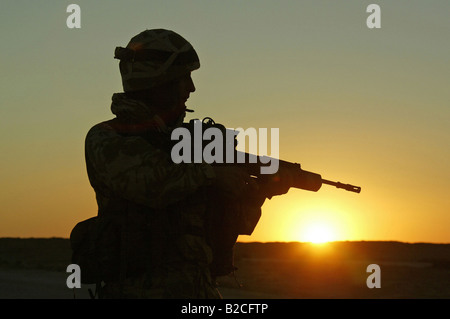 Soldato britannico di sentinella al tramonto nel deserto in Iraq Foto Stock