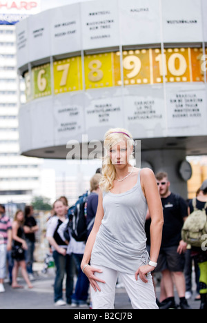 Donna bionda in posa davanti al famoso orologio mondiale Foto Stock