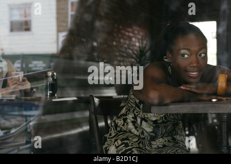 Felice giovane donna afro-americana in appoggio nella caffetteria. Foto Stock