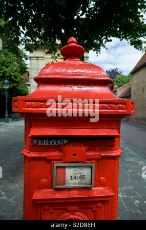 Un rosso postbox su una piazza di Bruges Foto Stock