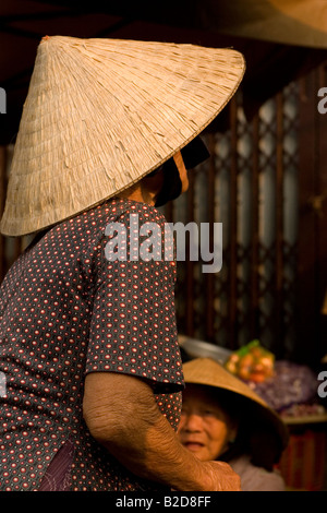 Donna che indossa il tradizionale 'Non La' cappelli conici opera al mercato di Hoi An, Vietnam. Foto Stock