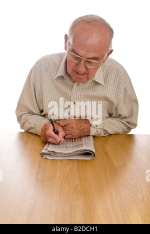 Ritratto verticale di un anziano gentiluomo facendo il puzzle Sudoku nel suo quotidiano Foto Stock