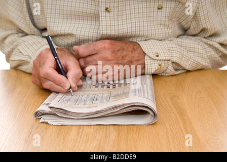 Ritratto orizzontale di un anziano gentiluomo facendo il puzzle Sudoku nel suo quotidiano Foto Stock
