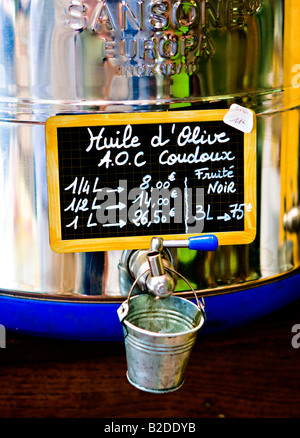 In prossimità di una canna di bulk di olio di oliva con una scritta a mano e segno della benna di piccole dimensioni per la degustazione. Foto Stock