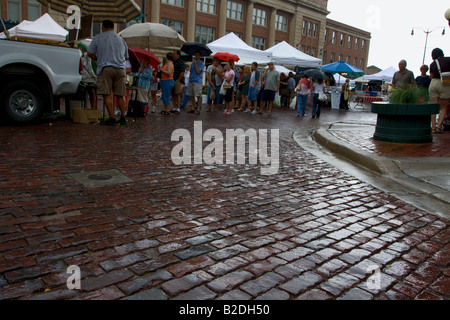In mattoni umidi street e ombrello in coda gli utenti presso il Lincoln, Nebraska Mercato degli Agricoltori. Foto Stock
