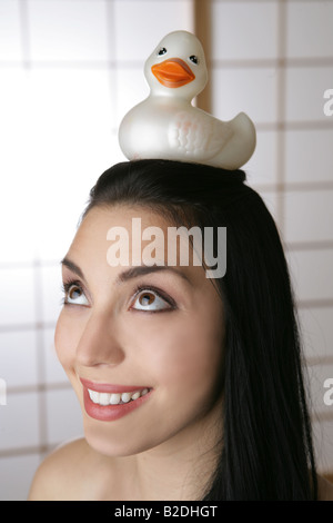 Giovane donna di bilanciamento anatra di gomma sulla testa. Foto Stock