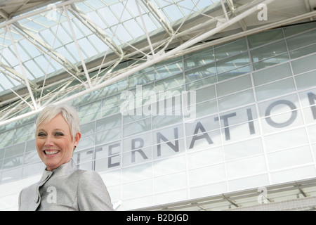 Donna matura in piedi di fronte all'aeroporto. Foto Stock