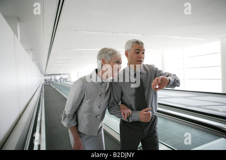 Coppia matura sul tapis roulant in aeroporto. Foto Stock