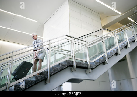 Donna matura tirando i bagagli al piano di sopra in aeroporto. Foto Stock
