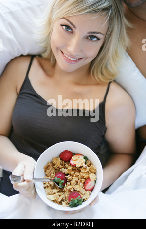 Angolo di Alta Vista della giovane donna di mangiare la colazione a letto. Foto Stock