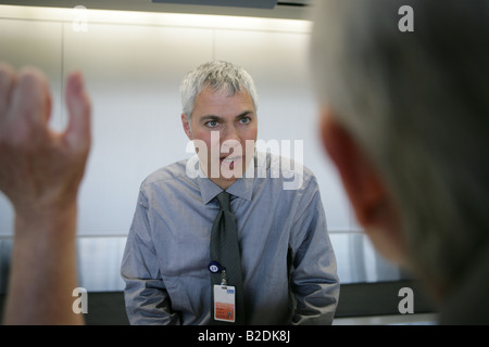 Controllare in attendant parlando con sottolineato passeggero al banco del check in. Foto Stock