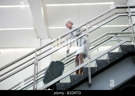 Donna matura tirando i bagagli al piano di sopra in aeroporto. Foto Stock