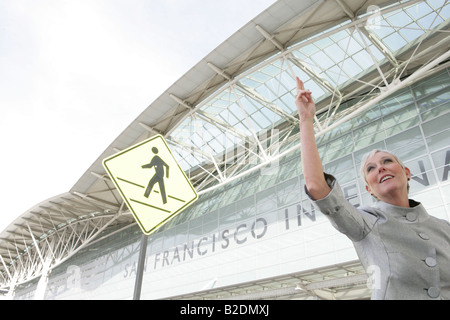 Donna matura salutando taxi all'aeroporto. Foto Stock