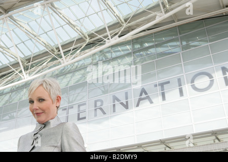 Donna matura in piedi di fronte all'aeroporto. Foto Stock
