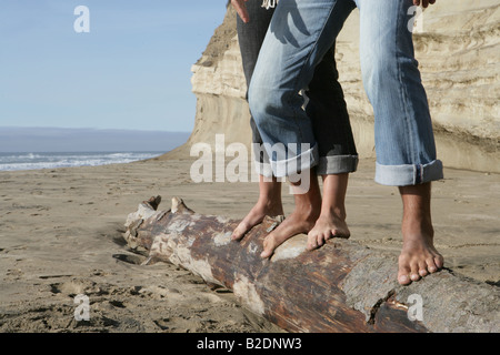 Vista ritagliata della giovane equilibratura su log in spiaggia. Foto Stock
