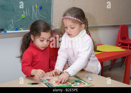 Due 4 anno di età pre school ragazze seduti ad un tavolo di fare un puzzle Foto Stock