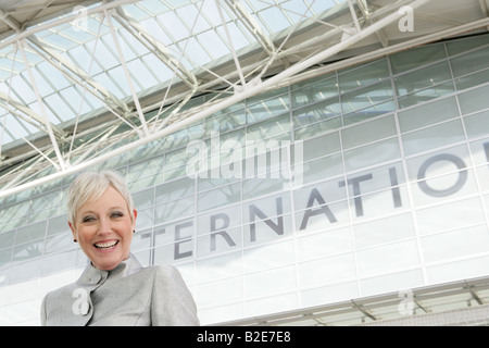 Donna matura in piedi di fronte all'aeroporto. Foto Stock