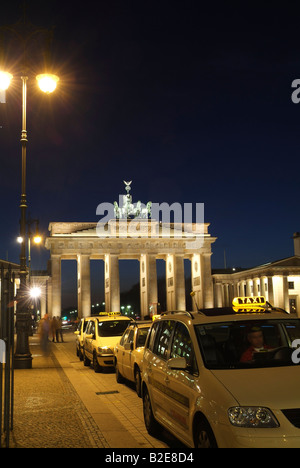 Taxi vicino al gate memorial accesa fino al crepuscolo e la Porta di Brandeburgo a Berlino Germania Foto Stock