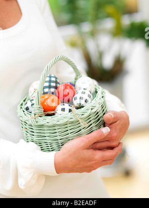 Metà vista in sezione della donna che la porta cesto di uova di pasqua Foto Stock