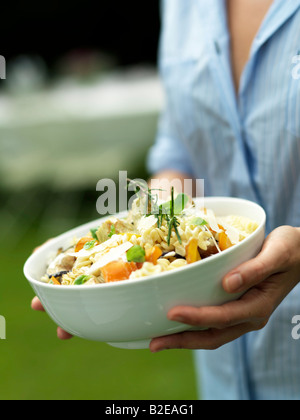 Metà vista in sezione della donna che mantiene una ciotola di insalata di pasta Foto Stock