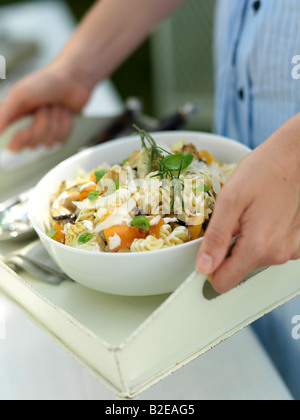 Metà vista in sezione della donna che mantiene una ciotola di insalata di pasta sul vassoio Foto Stock