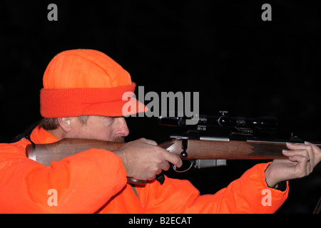 Un cacciatore dei cervi in hunter orange abbigliamento tenendo un alto powered rifle Foto Stock