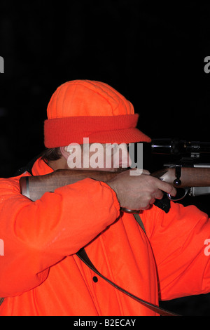 Un cacciatore dei cervi in hunter orange abbigliamento tenendo un alto powered rifle Foto Stock