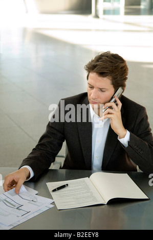 Imprenditore a parlare su un telefono mobile a una scrivania Foto Stock