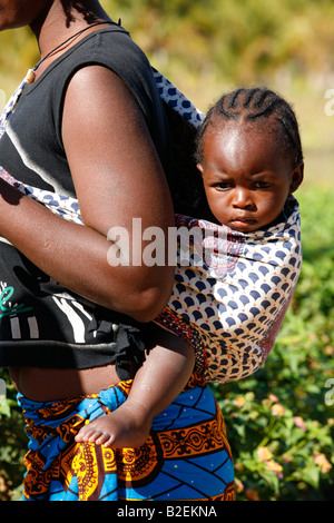 Ritratto di un curato bimbi africani portati in una imbracatura sulla sua madre indietro Foto Stock