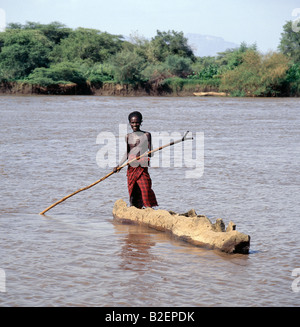 Un uomo Dassanech poli una scavata-out canoa attraverso le acque fangose di un affluente del fiume Omo nel suo delta vicino al lago Turkana. Foto Stock