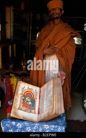 Un sacerdote a Kebran Gabriel Chiesa mostra uno dei suoi molti antichi libri illustrati. Foto Stock