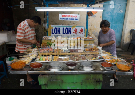 Malaysian venditore ambulante preparare snack su bastoni in corrispondenza di un lato della strada di stallo alimentare in Chinatown, Georgetown, Penang, Malaysia Foto Stock