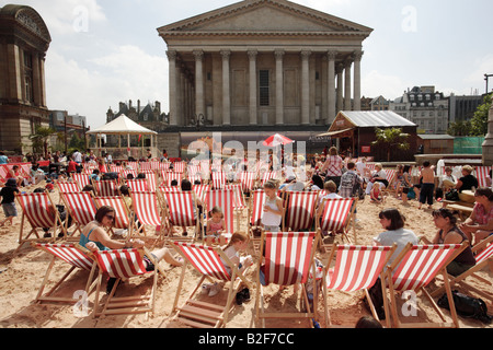 I visitatori di Birmingham's Chamberlain Square nel Regno Unito seduti in sedie a sdraio su una spiaggia artificiale. Foto Stock