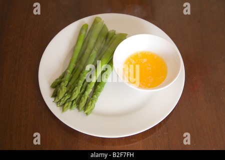 I germogli di asparagi e il burro dip su una porcellana bianca piastra. Foto Stock