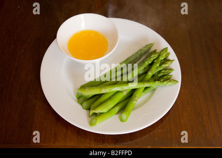 I germogli di asparagi e il burro dip su una porcellana bianca piastra. Foto Stock