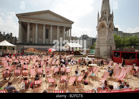 I visitatori di Birmingham's Chamberlain Square nel Regno Unito seduti in sedie a sdraio su una spiaggia artificiale. Foto Stock