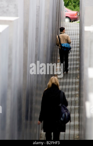 Berlino, due visitatori a piedi attraverso il campo di stele commemorativa per il assassinato ebrei d'Europa, vista posteriore Foto Stock