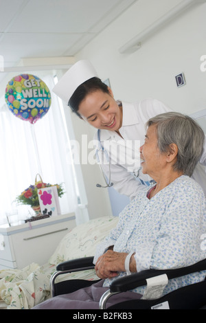 Infermiera femmina avendo cura di un paziente e sorridente Foto Stock