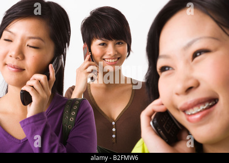 Tre giovani donne a parlare su telefoni cellulari Foto Stock